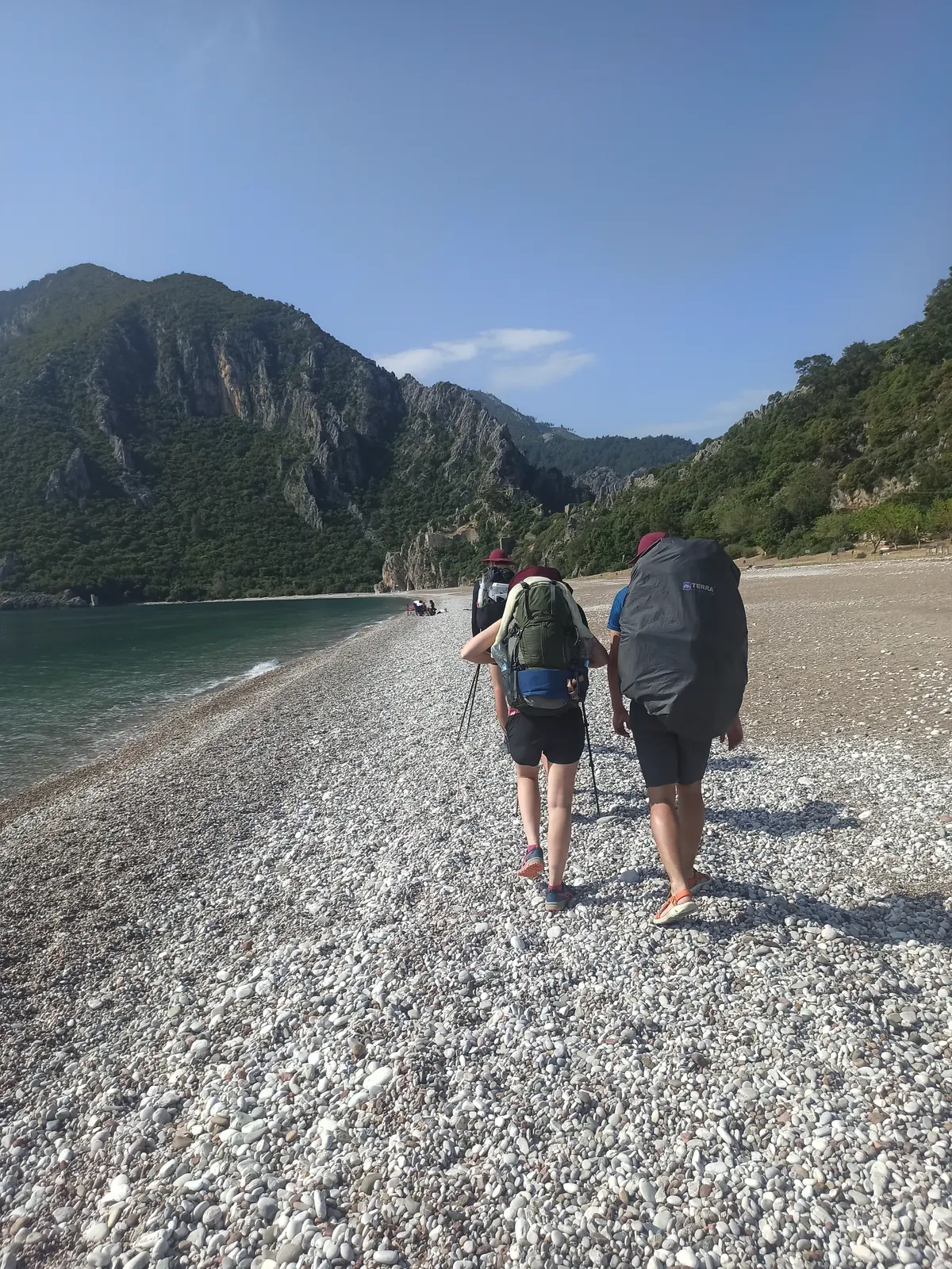 Two hikers walking along a pebble beach