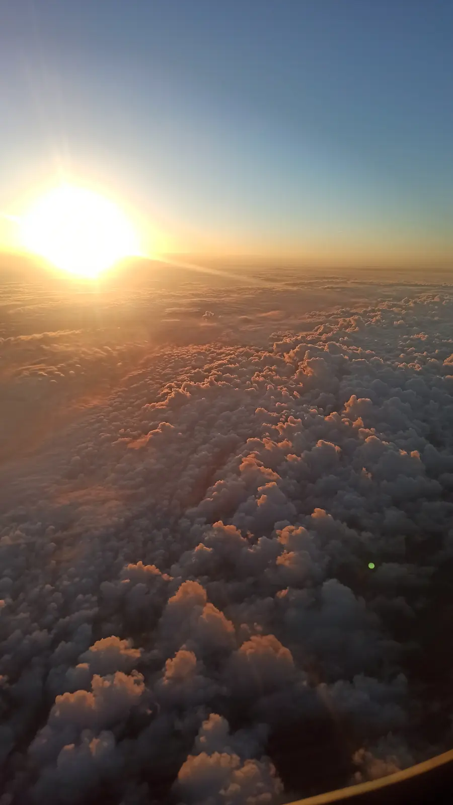Low sun over a field of clouds lit orange