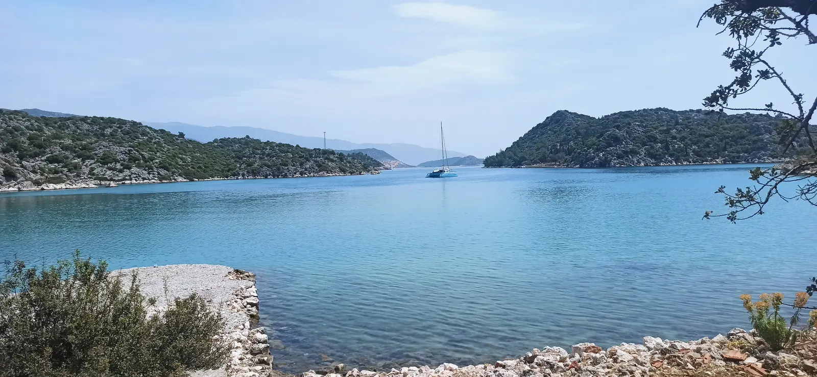 A calm turquoise bay with yachts at anchor between green islands