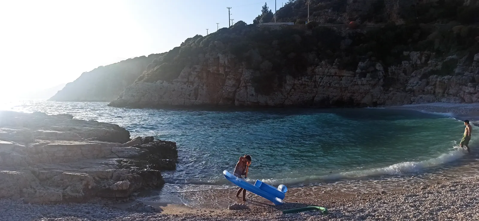 A small rocky cove with clear water and a kayaker on the shore