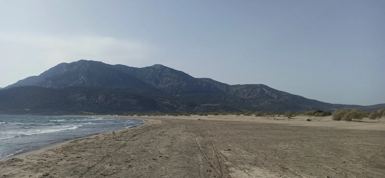 A long empty sandy beach leading to mountains