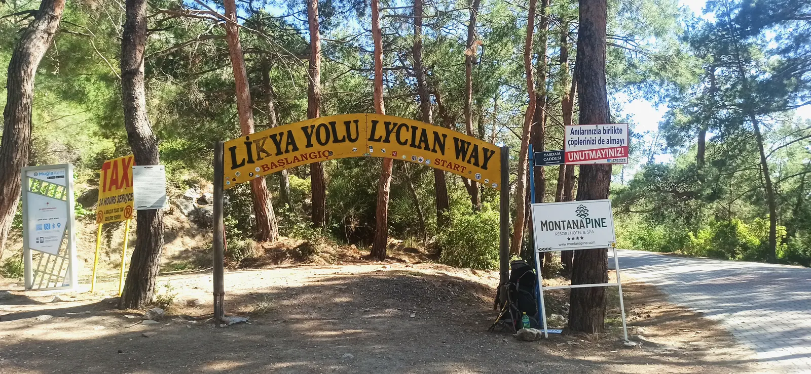 A wooden arch reading Likya Yolu Lycian Way over a path between pines