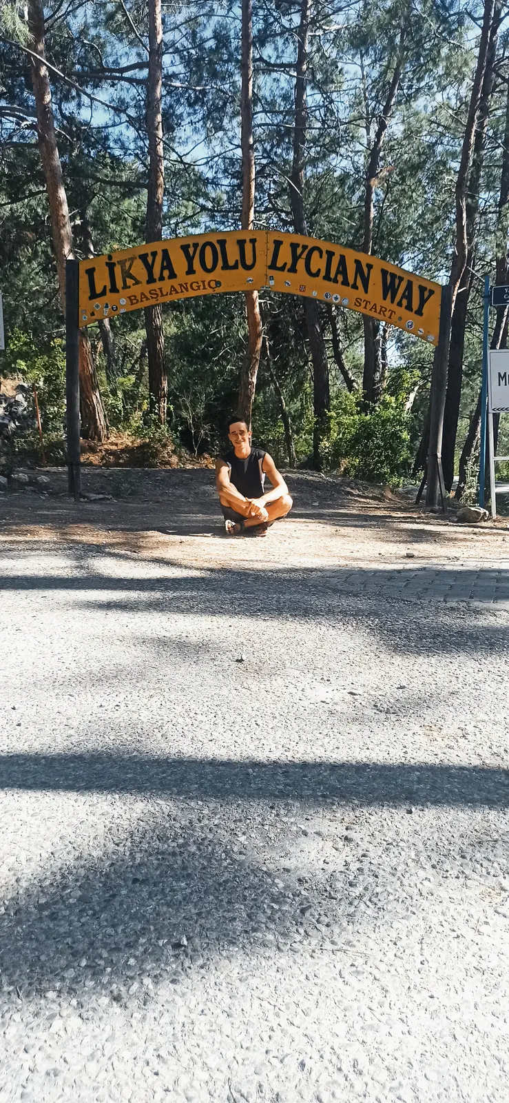 Andrii sitting on the ground under the Lycian Way arch