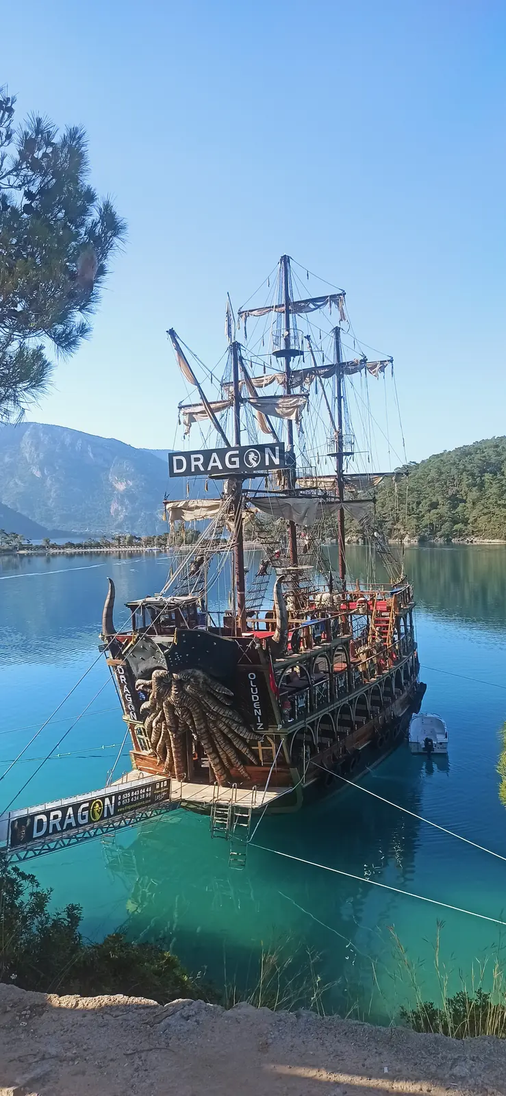 A wooden pirate-style tourist ship moored in turquoise water