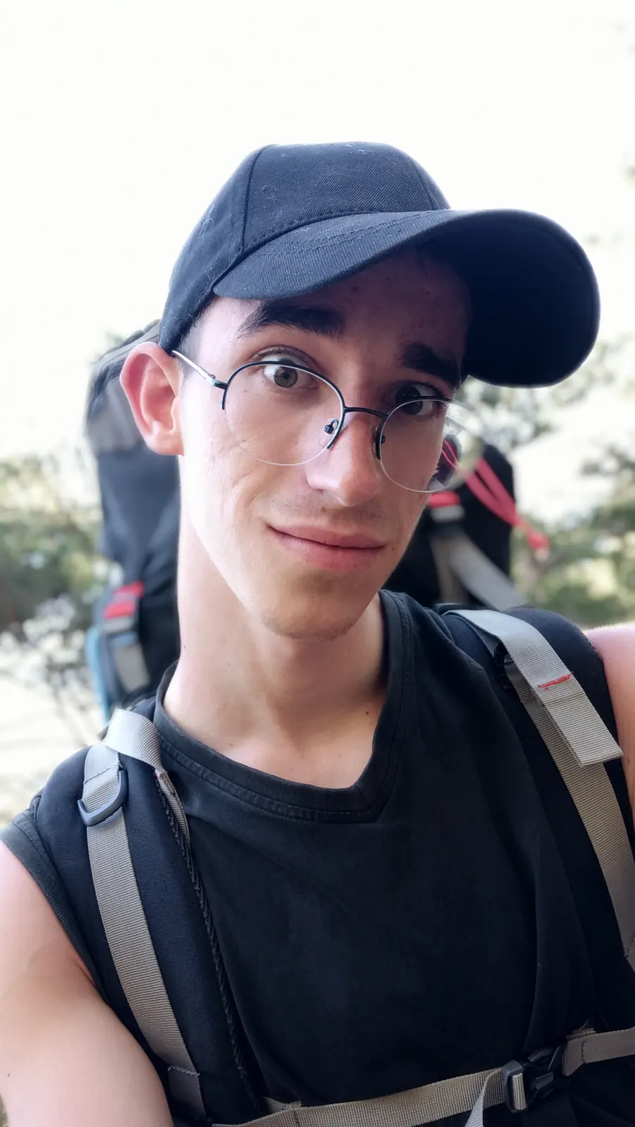 Close-up selfie of Andrii in a black cap with backpack straps