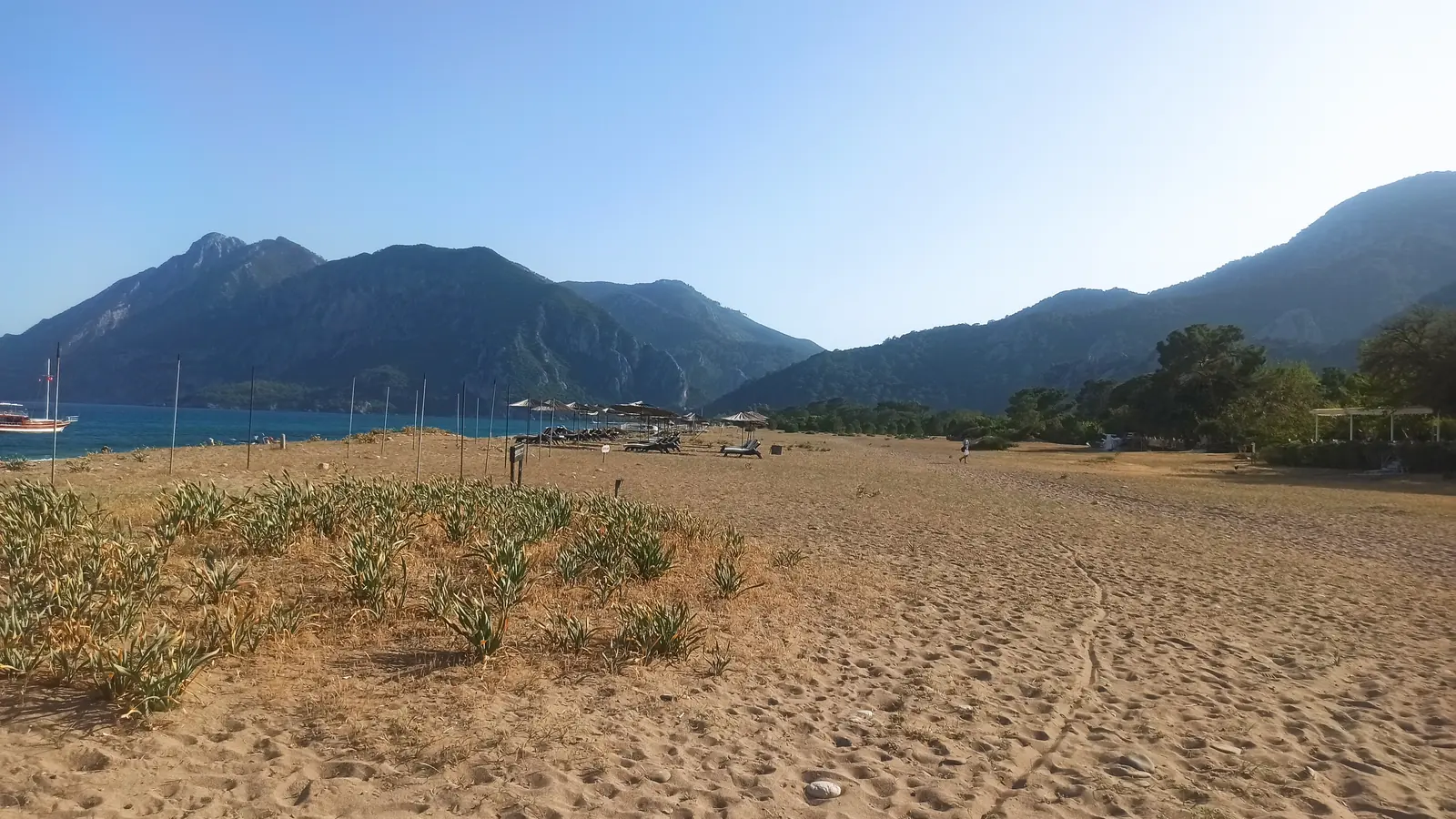 A sandy beach with a bay and mountains on the far side
