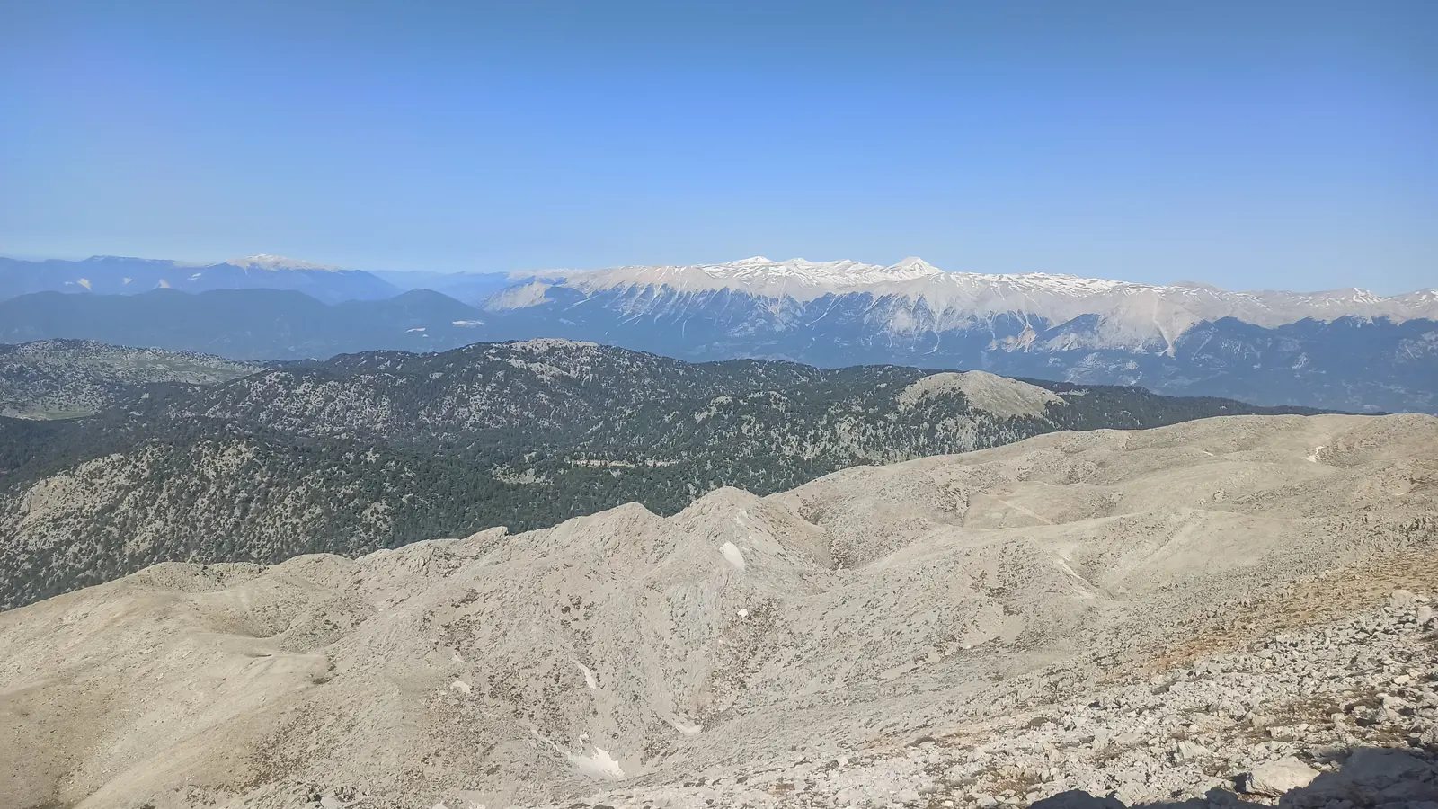 View from a bare white mountainside down to a coastline and the sea