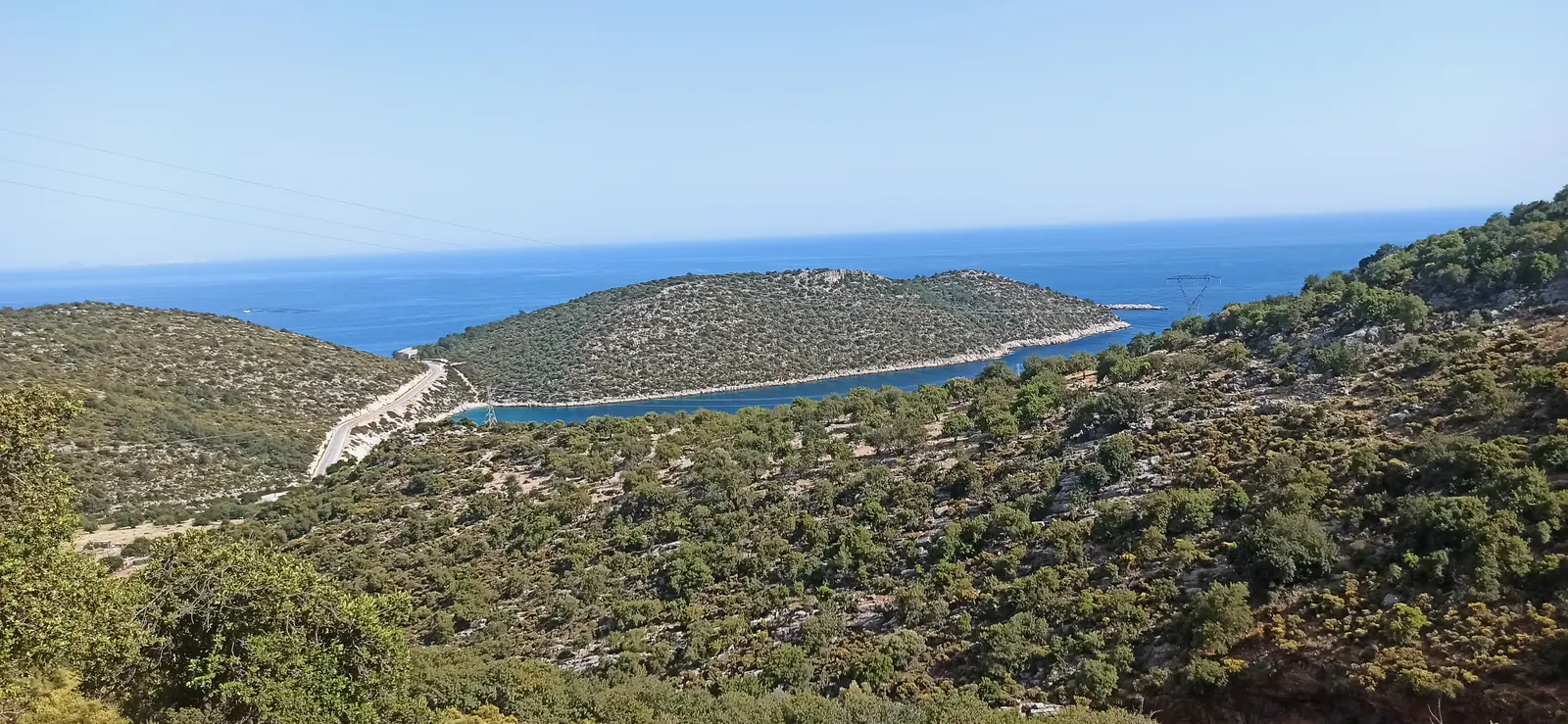 A long green headland enclosing a blue bay