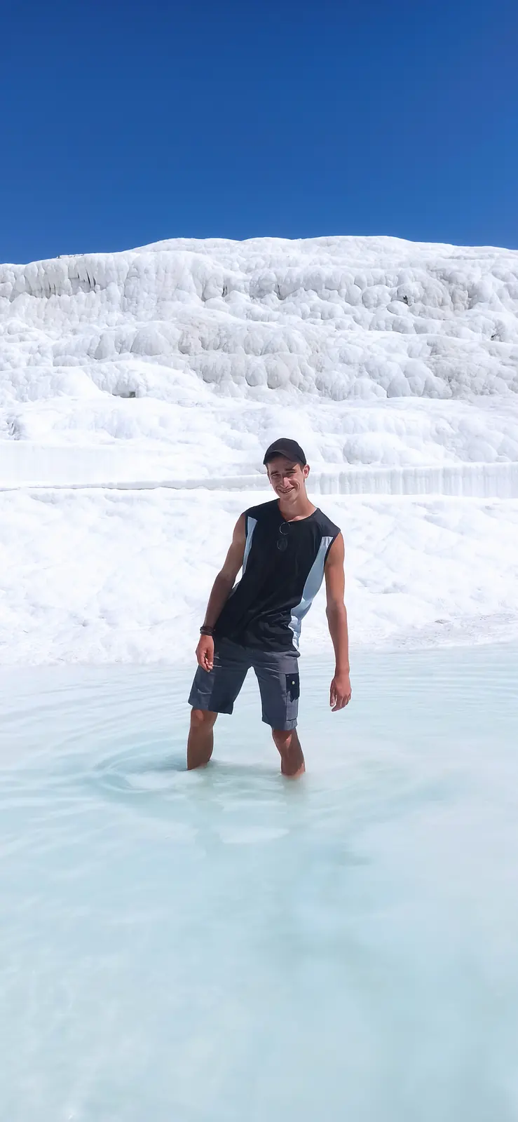 Andrii standing knee-deep in a pale blue travertine pool
